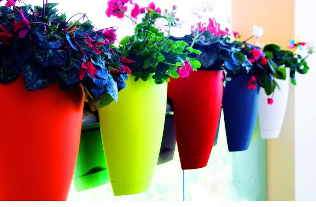 GoHooked 12-inch railing planters in red, lime green, blue, and white, holding colorful flowers.