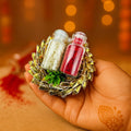 GoHooked multicolor designer Rakhi with roli and chawal in glass vials, held in a hand with mehndi.