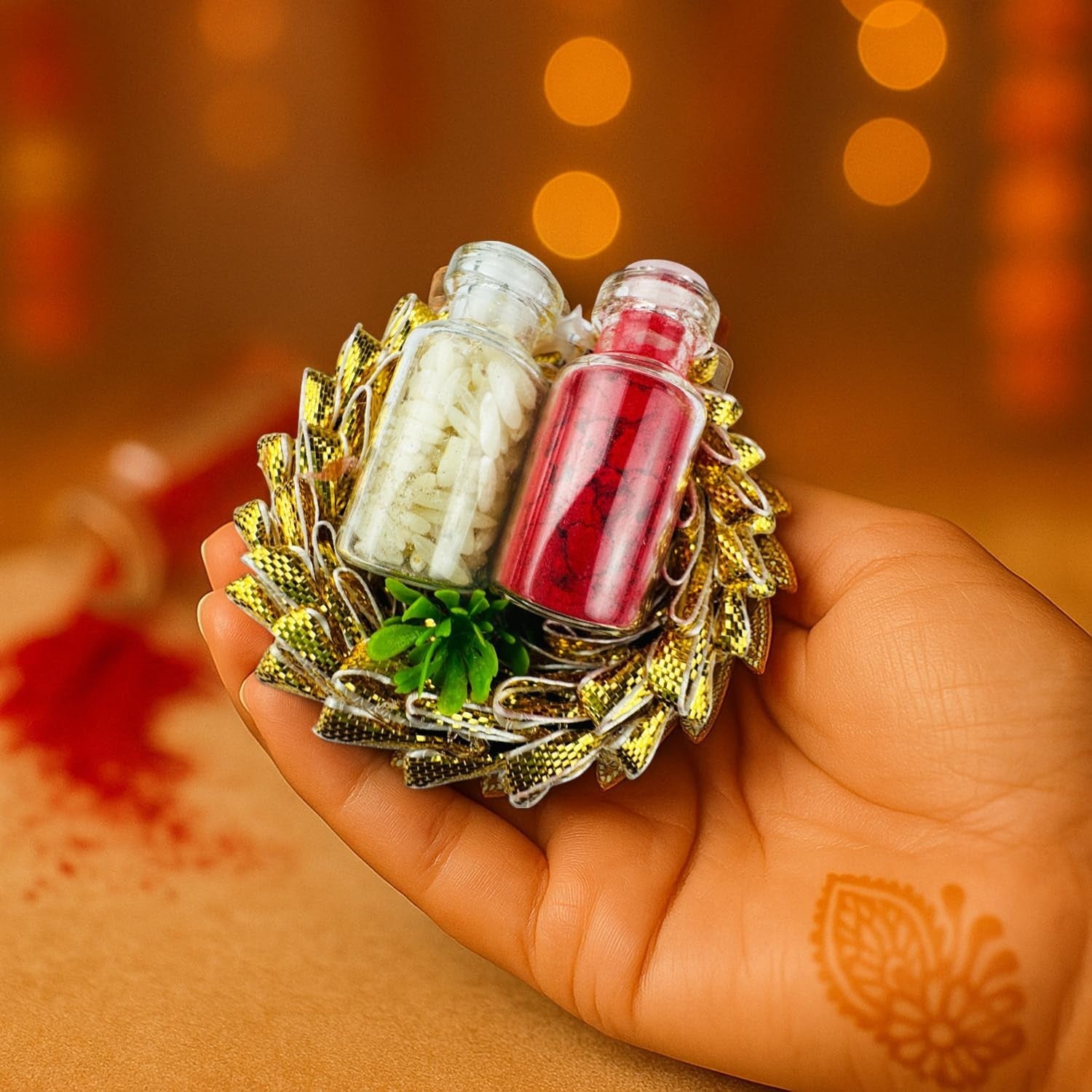 GoHooked designer Rakhi with red kumkum and white rice in glass vials, on a golden decorative base held in a hand.