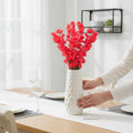 Go Hooked red artificial flowers in a white textured vase on a dining table.