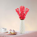 Go Hooked red artificial flowers in a textured white ceramic vase, with pastries and tea on a pink tablecloth.