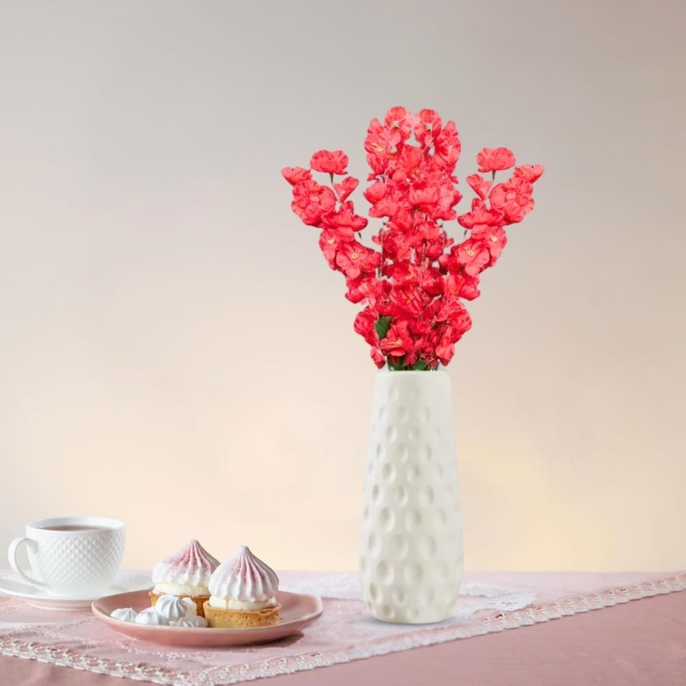 Go Hooked red artificial flowers in a textured white ceramic vase, with pastries and tea on a pink tablecloth.
