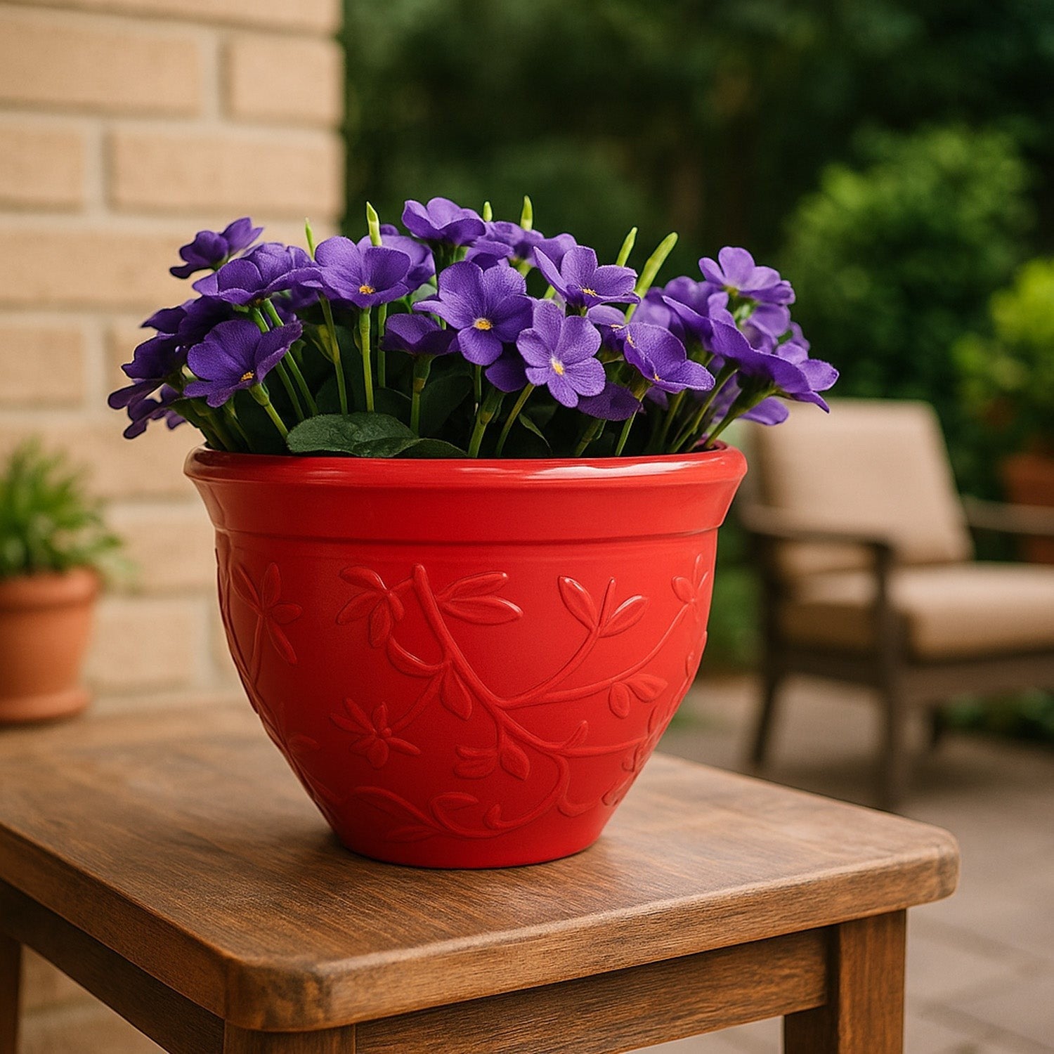 GoHooked red plastic Victory planter pot with embossed floral pattern holding purple flowers on a wooden table