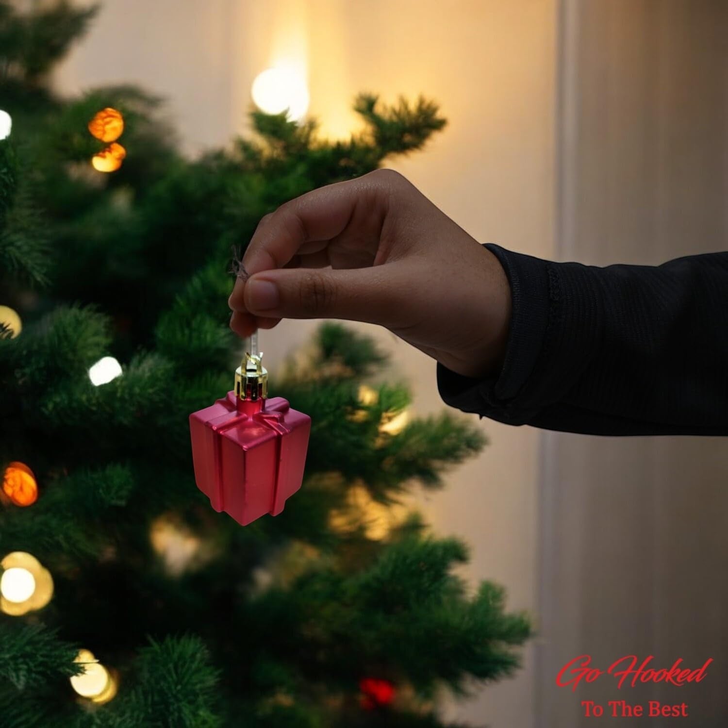 Go Hooked red glitter gift box Christmas ornament hanging on a tree. Festive home decor.