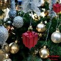Go Hooked red glitter gift box Christmas ornament hanging on a decorated tree with gold and silver baubles.