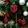 Go Hooked red gift box Christmas ornaments with glitter accents, hanging on a decorated tree.