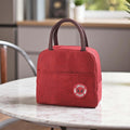 GoHooked red insulated lunch bag with brown handles and a circular panda patch on the front.