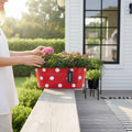 GoHooked red metal oval hanging planter with white polka dots, filled with pink and purple flowers.