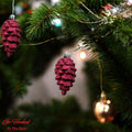 Go Hooked red pine cone Christmas ornaments with glitter details hanging on a decorated tree.