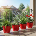GoHooked red 8-inch plastic planters with trays, set of 4, holding various plants on a balcony.