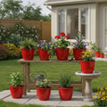 Go Hooked red 10-inch plastic planters with various plants arranged on a bench and patio.