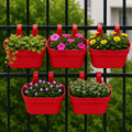 GoHooked set of 5 red plastic railing hanging planters filled with flowers and greenery on a black fence.