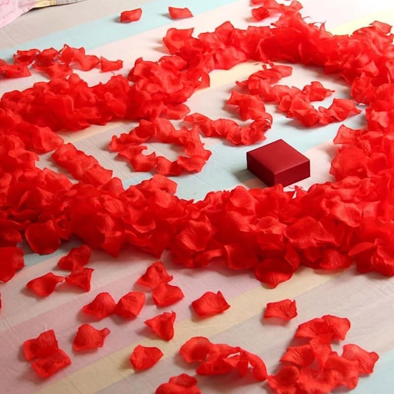GoHooked red artificial rose petals and tealight candles arranged on a striped surface with a small red gift box.