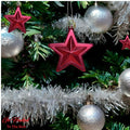 GoHooked red star Christmas ornaments with glitter accents, hanging on a decorated tree with silver baubles and tinsel.