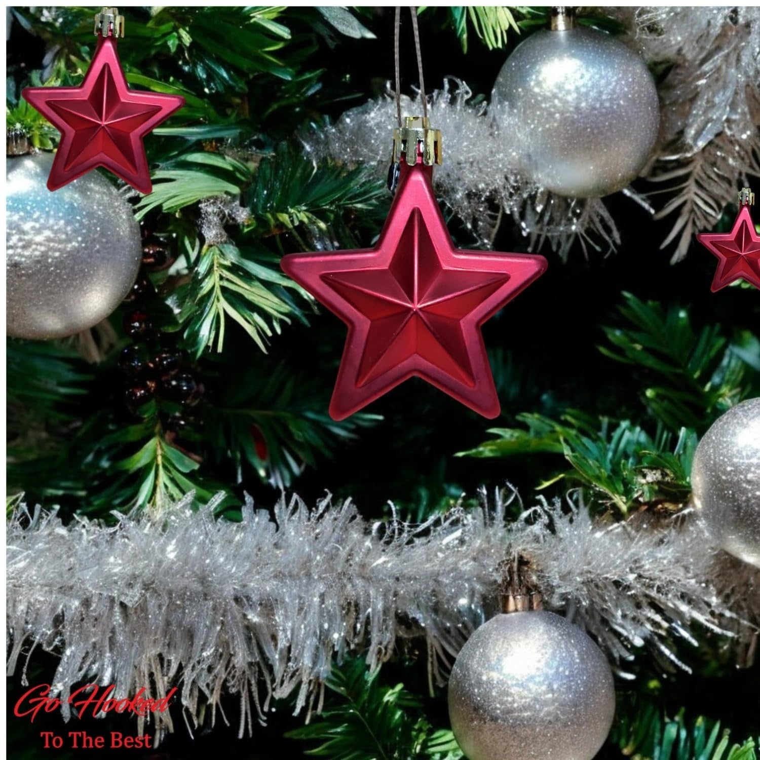 GoHooked red star Christmas ornaments with glitter accents, hanging on a decorated tree with silver baubles and tinsel.