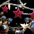 Go Hooked red star ornaments with glitter accents, part of a festive Christmas tree decor with blue and gold baubles and fairy lights.