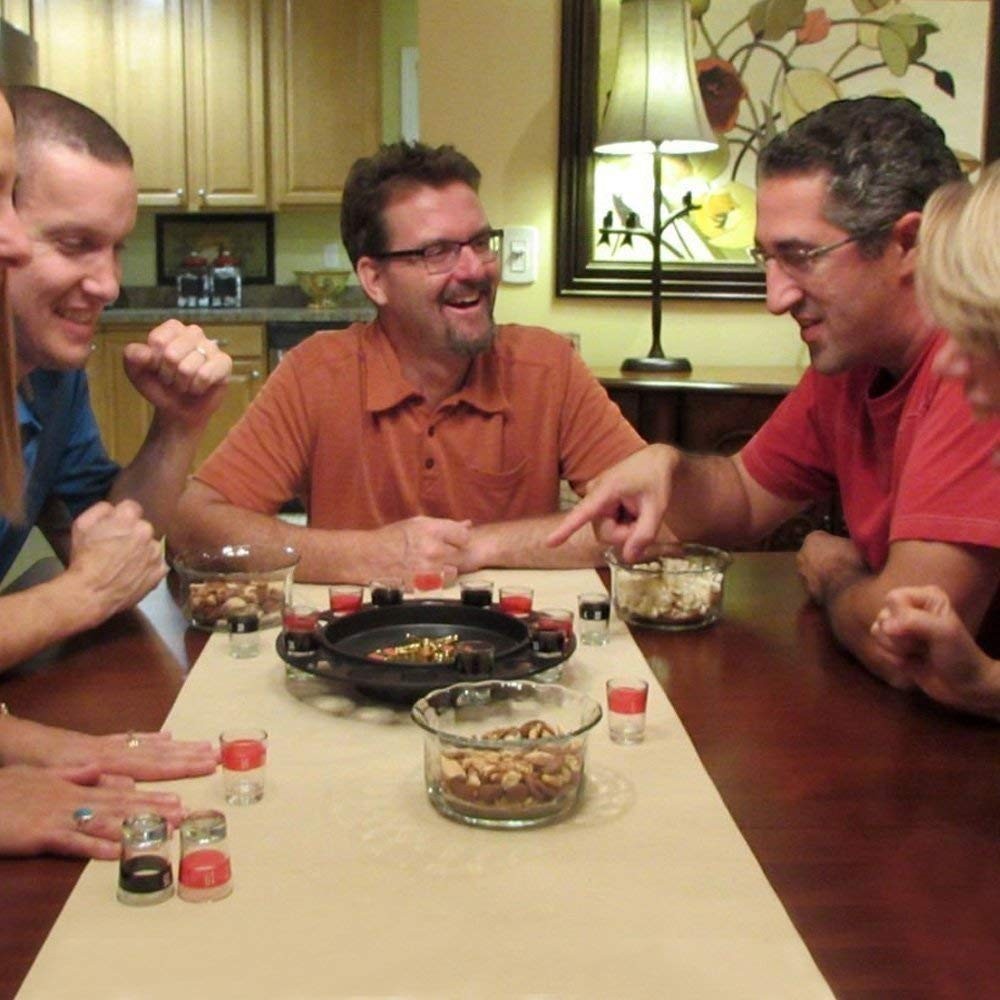 GoHooked roulette drinking game set with 16 shot glasses, casino party game for adults, friends playing at a table with snacks.