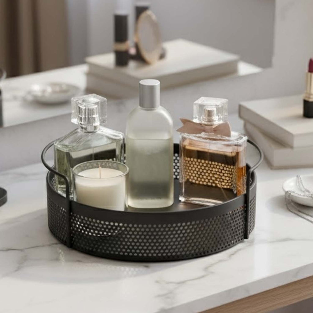 GoHooked round black metal storage tray with perforated sides and handles, holding perfume bottles and a candle.
