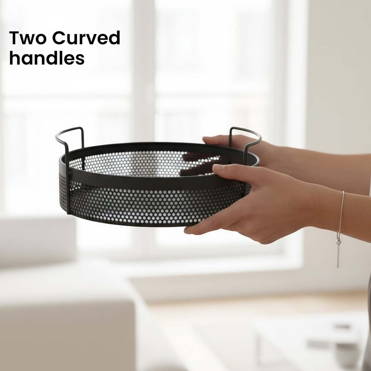 GoHooked round black metal storage tray with perforated design and two curved side handles held by a person