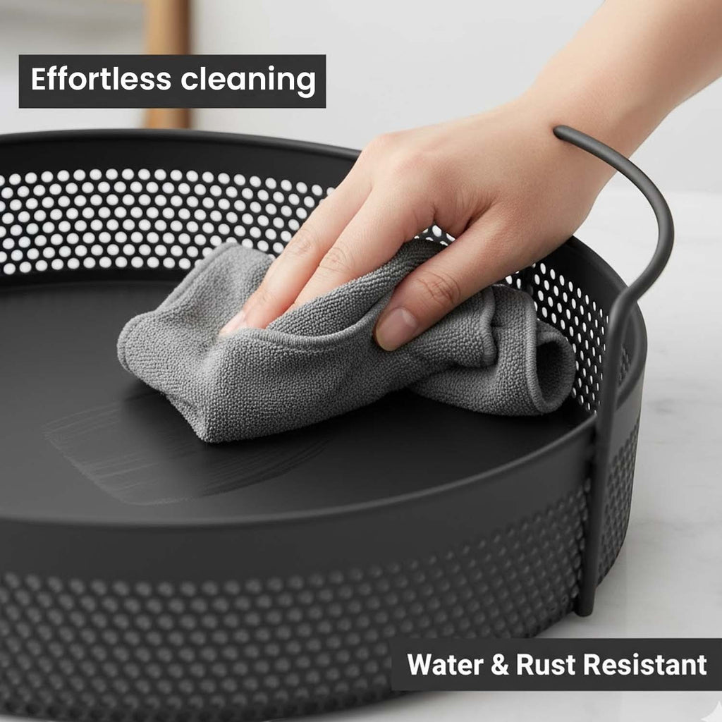 GoHooked round black metal storage tray with perforated sides and handles being wiped clean with a cloth.