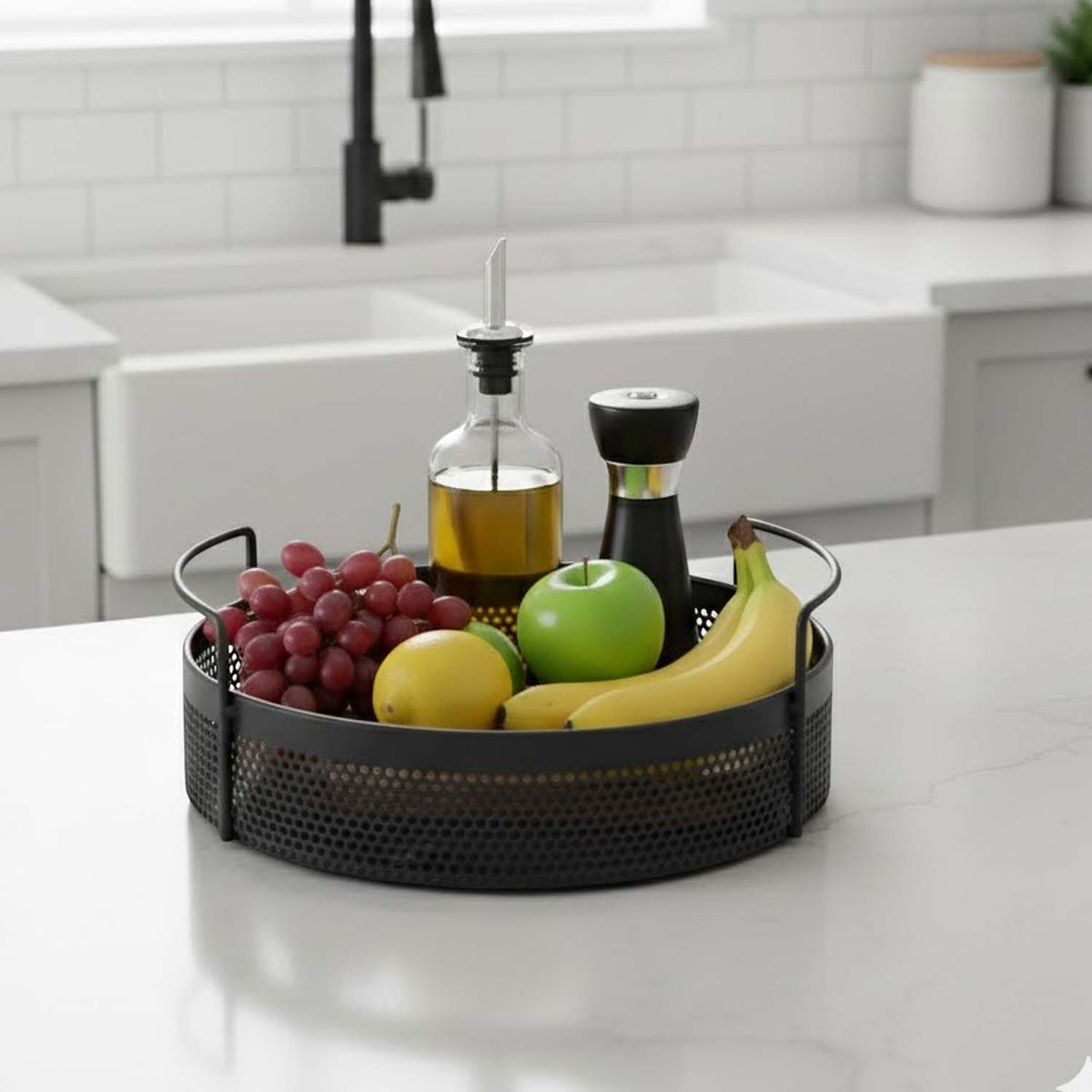 GoHooked round black metal storage tray with perforated design and side handles holding fruit on a kitchen counter