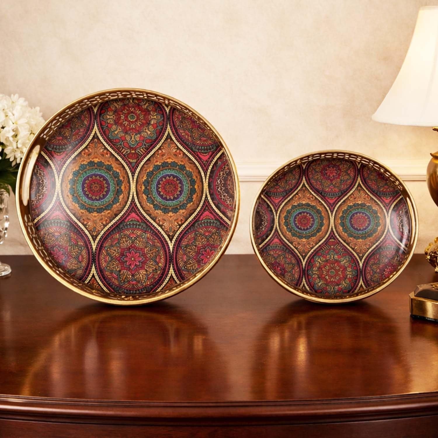 Go Hooked set of 2 round metal decorative trays with gold finish and intricate geometric art in red, gold, teal, and brown.