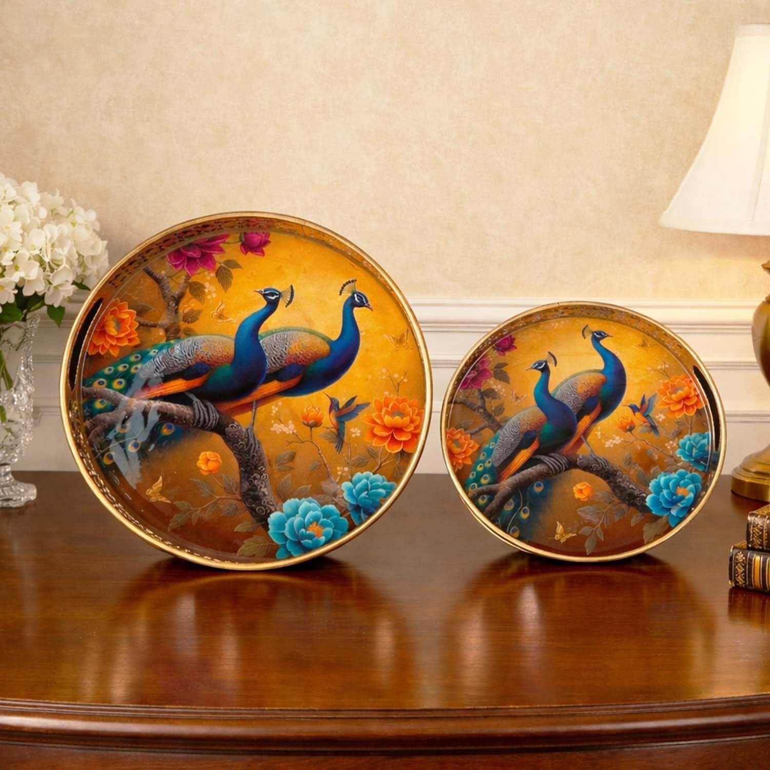 Go Hooked set of 2 round metal decorative trays with gold finish, featuring peacocks on a branch with vibrant flowers.