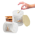 GoHooked ViMe Sandalwood Serenity aroma candle in a white jar, lit with a match. Includes raw sandalwood pieces.