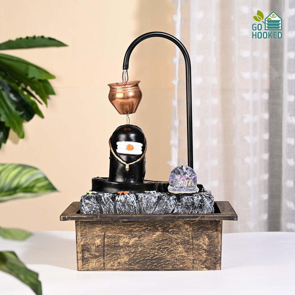 GoHooked Shivling water fountain with copper kalash drip, LED crystal ball, and adjustable water flow. Matte black polyresin.