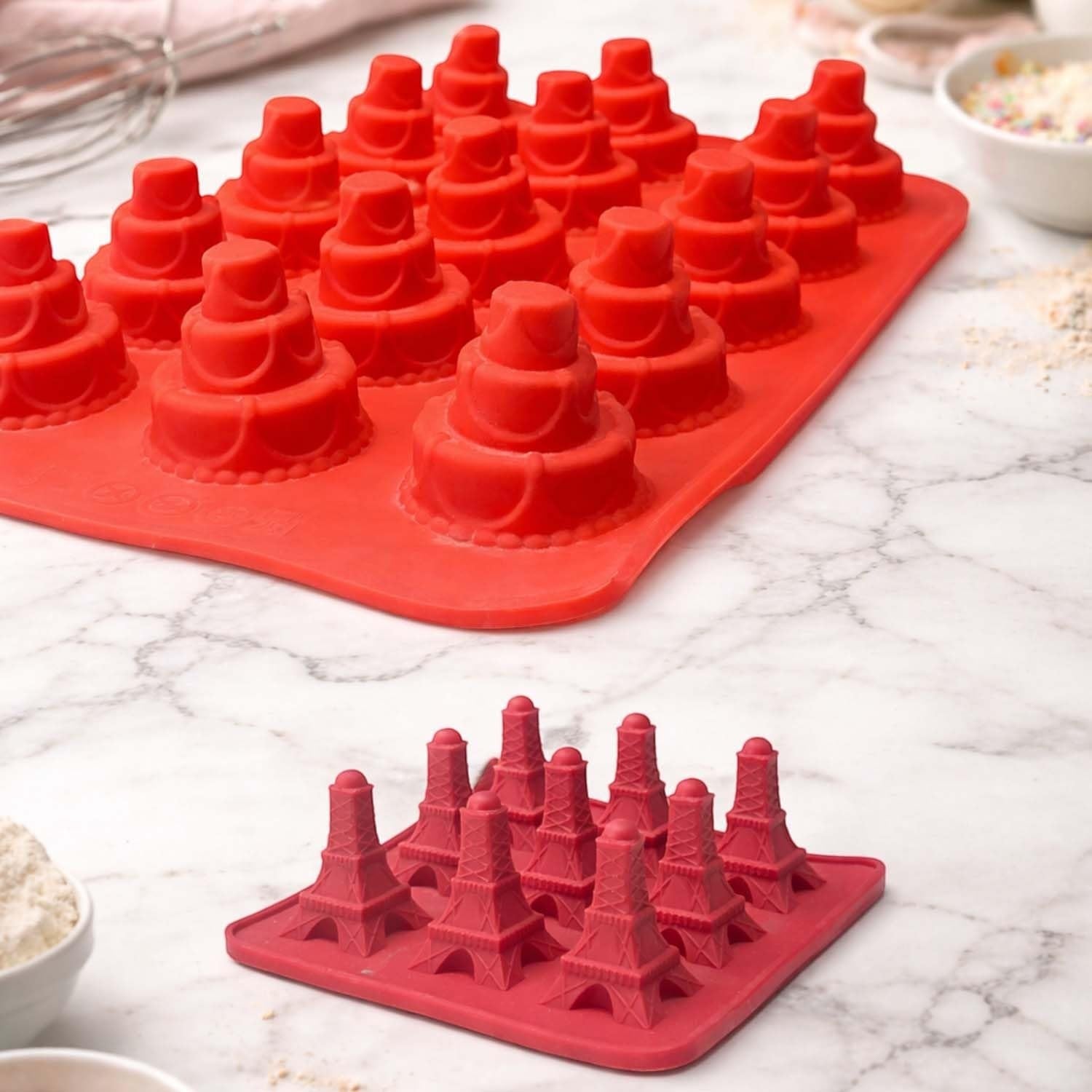 GoHooked red silicone molds for baking cakes and chocolates with tiered cake and Eiffel Tower shapes on marble surface