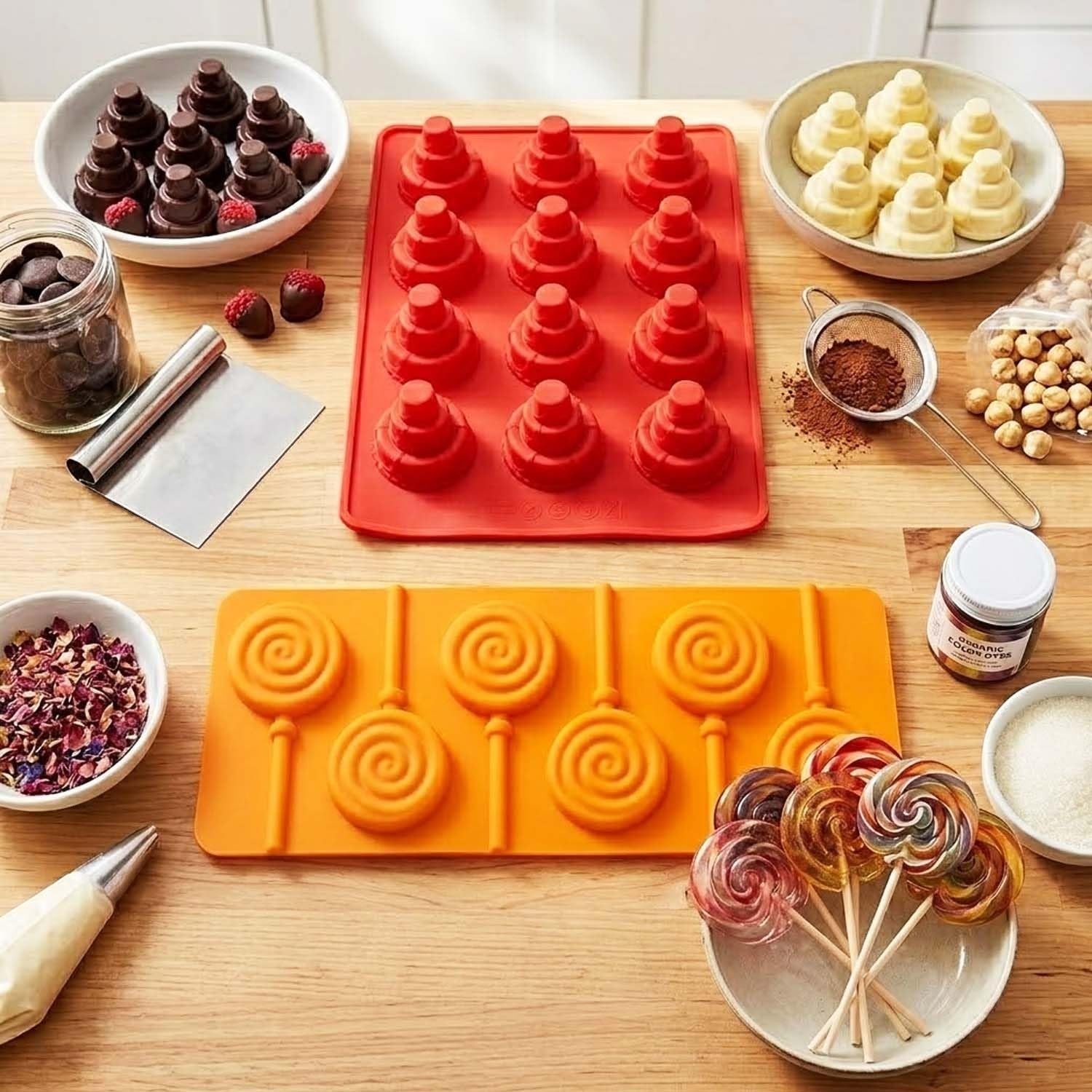 GoHooked silicone baking molds for chocolates and lollipops on a wooden table with ingredients and finished treats.
