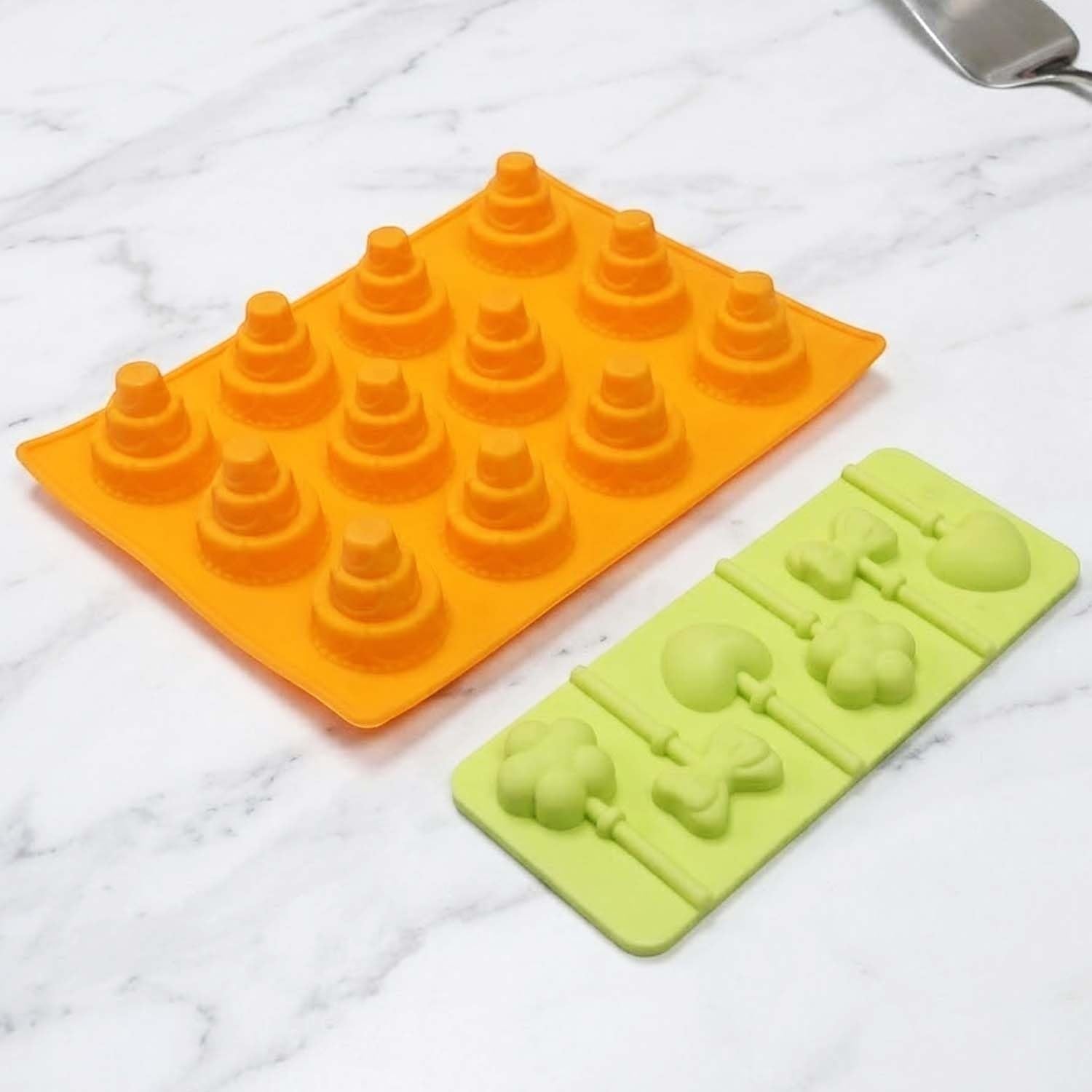 GoHooked silicone chocolate molds in orange and light green with cake and lollipop shapes on a marble surface