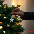 Go Hooked silver glitter star Christmas ornament being held up to a decorated tree.