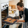 GoHooked grey square carbon steel baking pan with four mini pizzas, 23.5 x 22 x 5 cm.