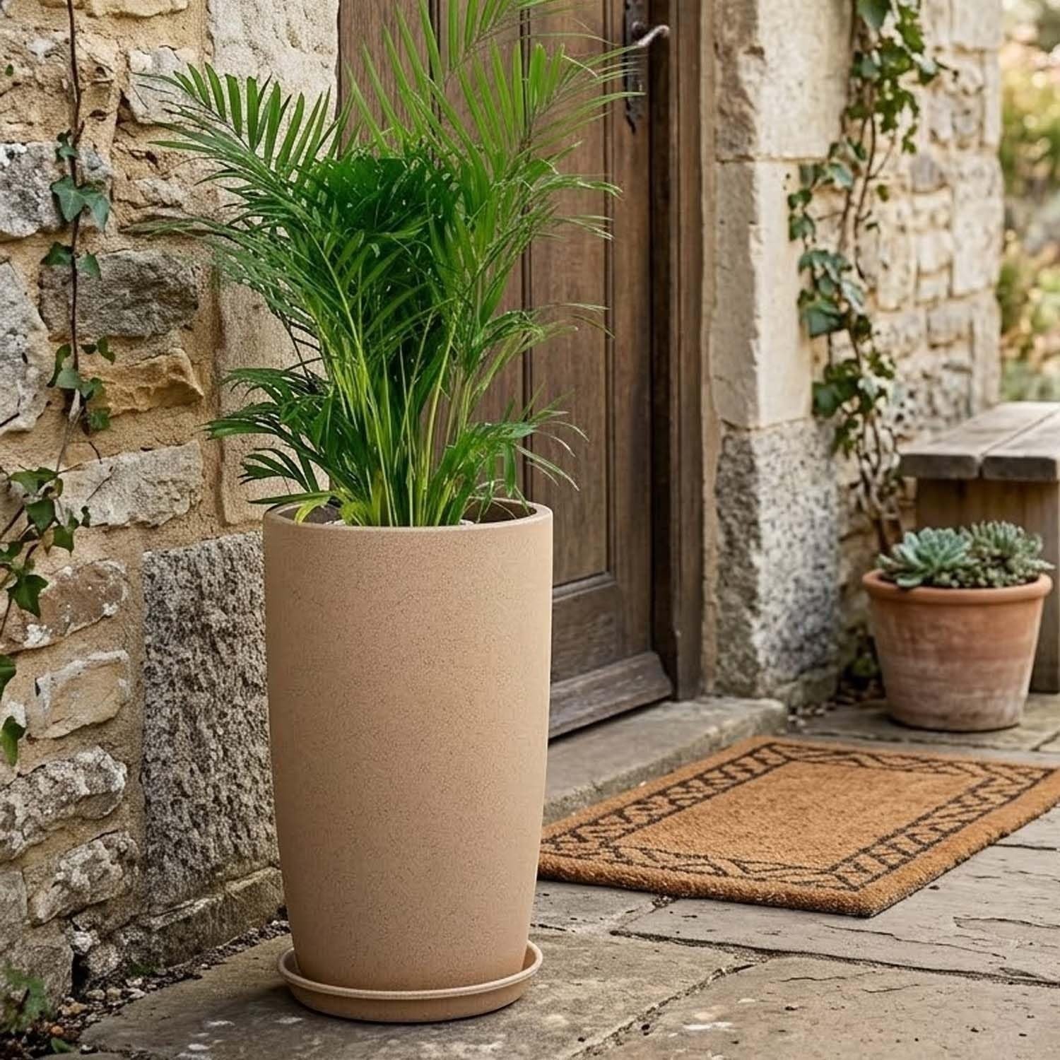 GoHooked tall, cylindrical beige plastic planter with a matching saucer, holding a lush green palm plant. Outdoor setting.
