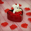 GoHooked white teddy bear with "I Love You" sign sits in a red heart-shaped box with red roses and petals.