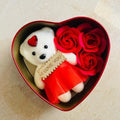 GoHooked white teddy bear with red dress and "I Love You" tag in a heart-shaped tin box with red roses.