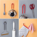 GoHooked transparent adhesive hooks holding kitchen utensils, scissors, lint roller, and oven mitt.