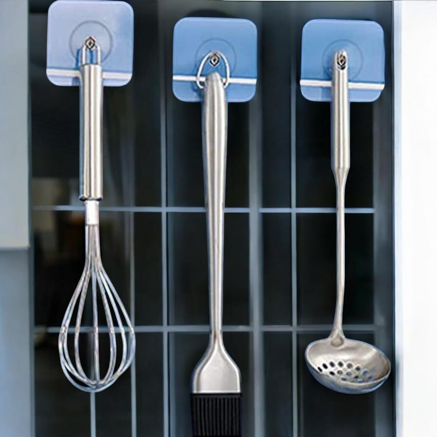 GoHooked transparent adhesive hooks holding a whisk, pastry brush, and ladle. Heavy-duty, waterproof, no-drill wall mounts.