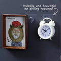 GoHooked transparent adhesive hooks holding a framed picture and a white alarm clock. No drilling required.