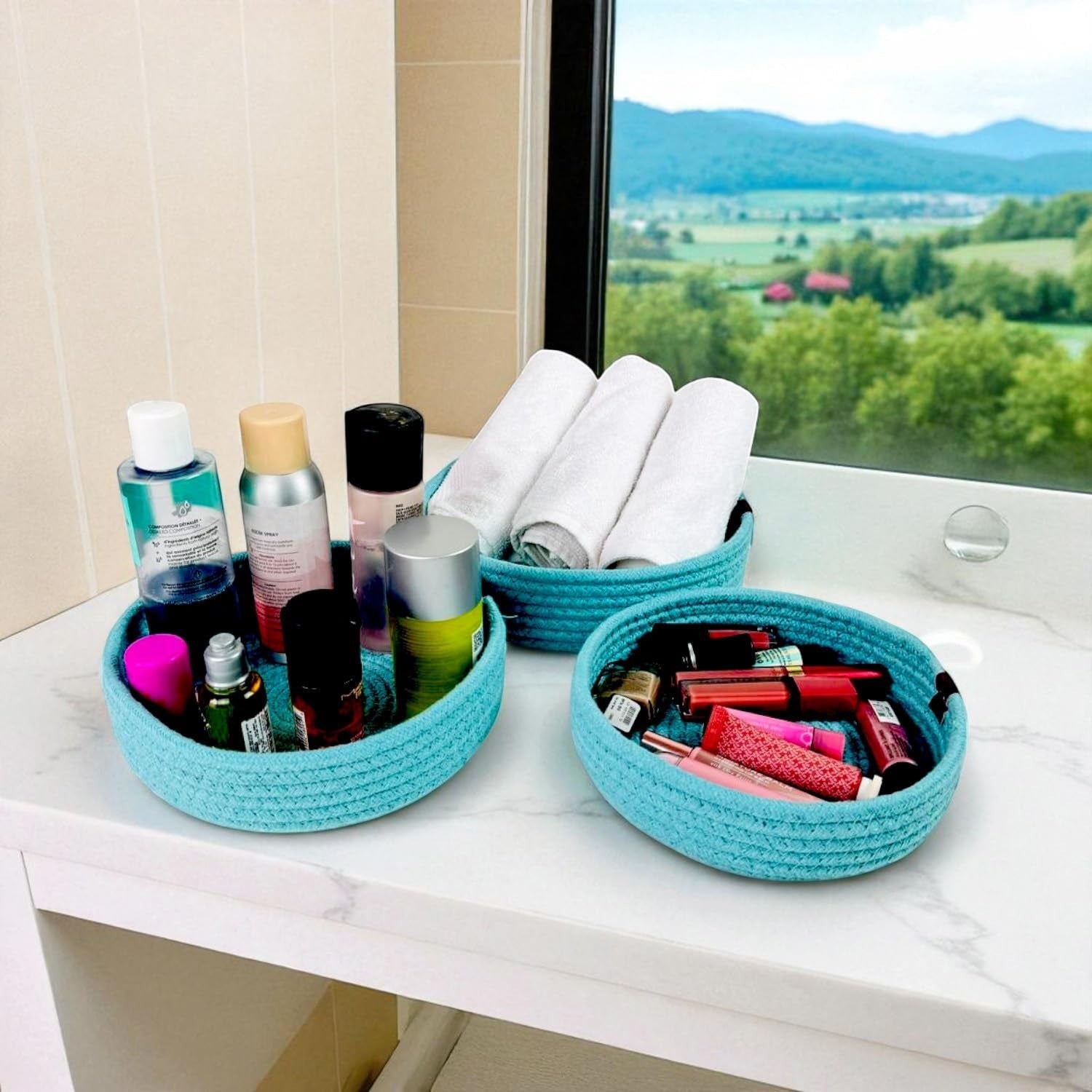 GoHooked set of three round turquoise cotton rope storage baskets on a white vanity holding toiletries and towels.
