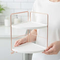 GoHooked Two-Tier Corner Vanity Organizer Shelf with white shelves and rose gold frame. Perfect for makeup and skincare.
