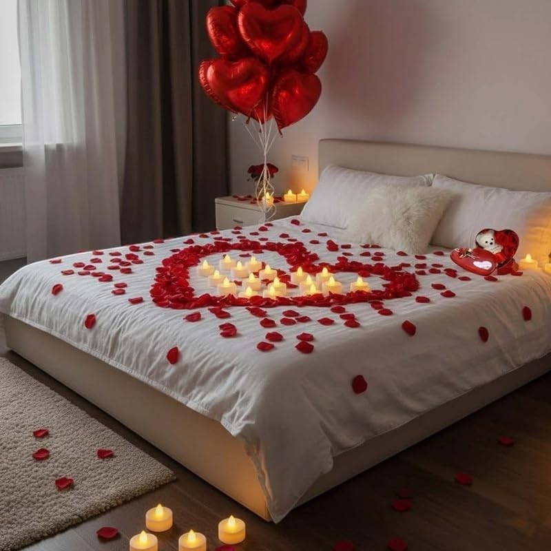 Go Hooked Valentine's Day decor set with red rose petals, LED tea lights forming a heart, and red heart balloons on a bed.