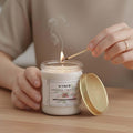 GoHooked ViMe white glass jar candle with lasting lily scent, lit by a match. Ideal for aromatherapy and home decor.