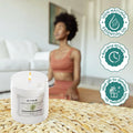 GoHooked ViMe Bamboo & White Tea scented candle in a clear jar, burning with a gentle flame. Woman meditating in background.