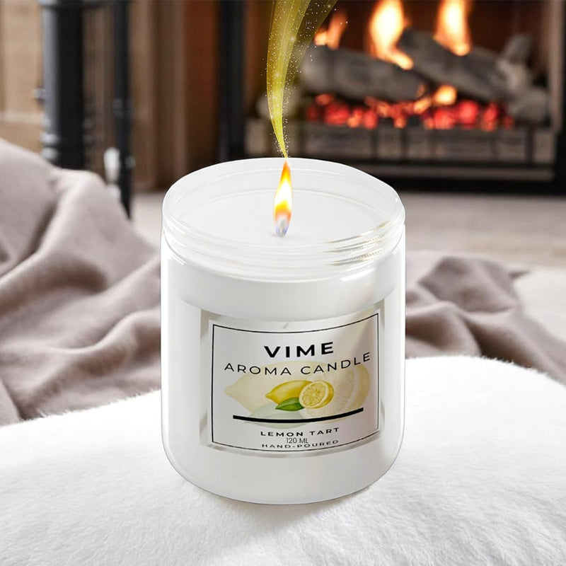GoHooked ViMe Lemon Tart scented candle in a white jar, burning with a warm flame, set by a fireplace.