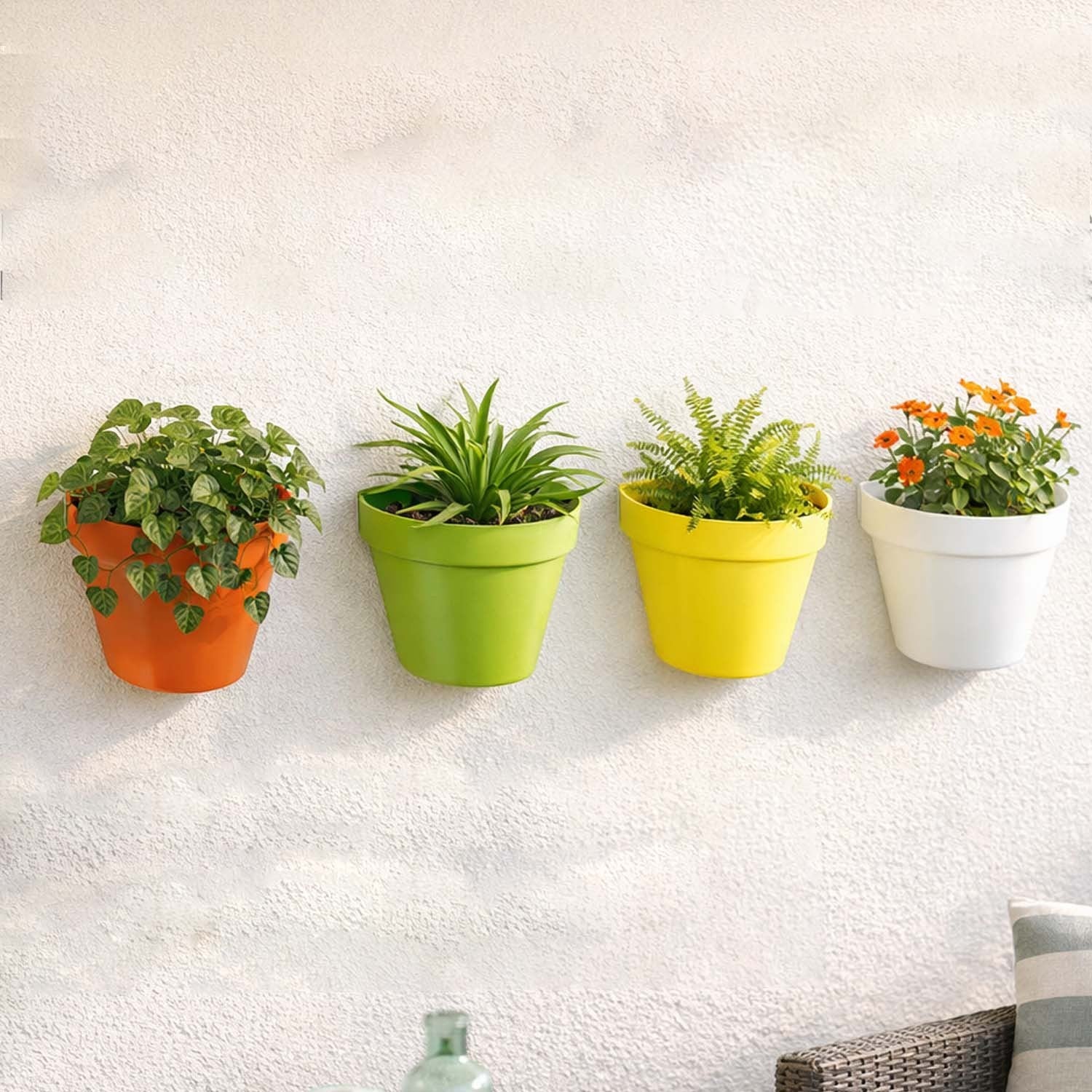 GoHooked set of four colorful plastic wall-mounted planters in orange, lime green, yellow, and white on a wall.