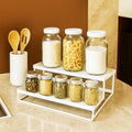GoHooked white 2-tier metal standing rack organizer holding jars of spices, pasta, and milk. Includes wooden utensils.