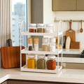 GoHooked white 3-tier curved metal vanity organizer with jars of spices and seasonings on a kitchen counter.