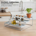 GoHooked white 3-tier metal spice rack organizer for kitchen counter or cabinet. Holds jars, bottles, and a potted herb.